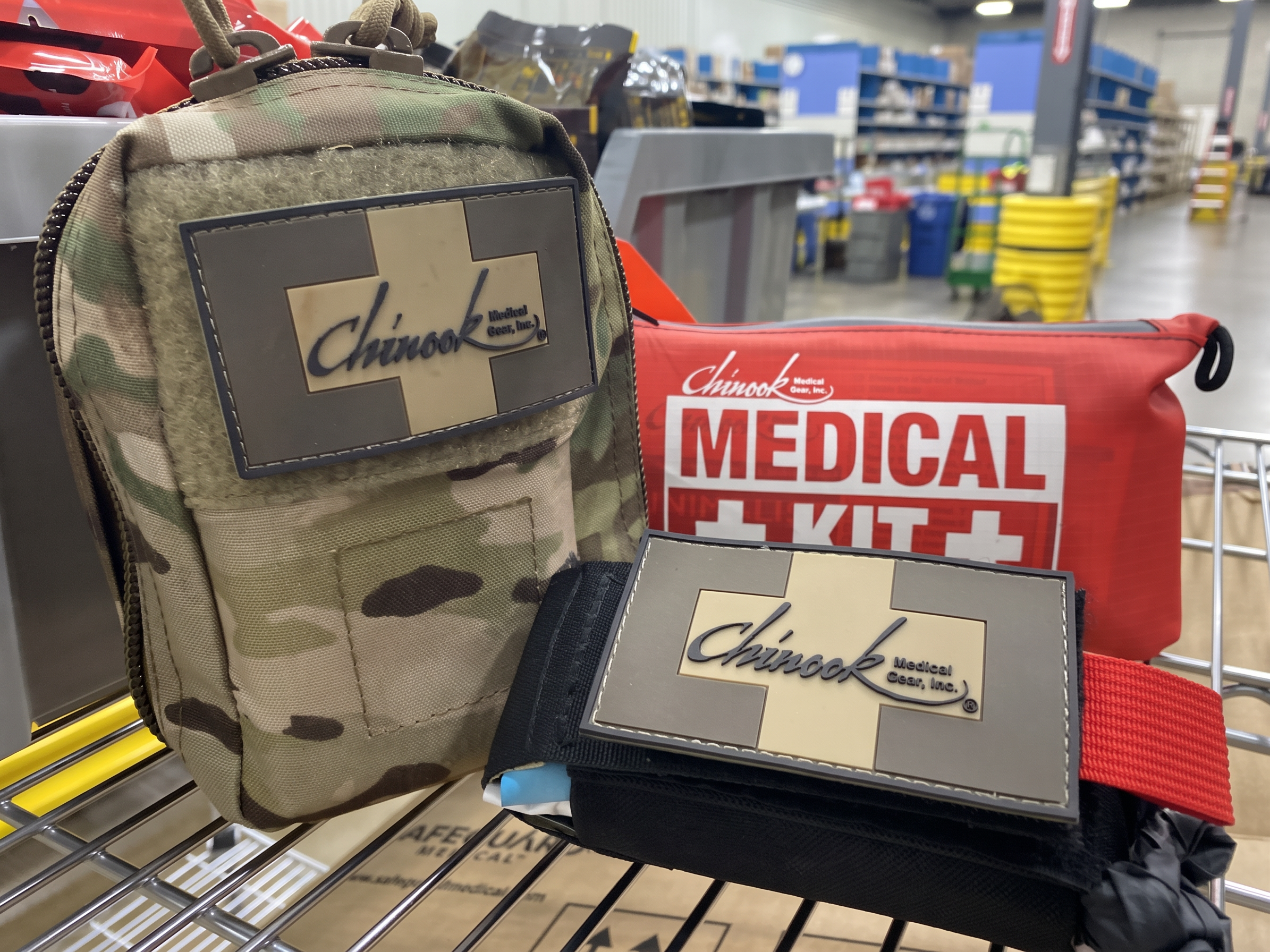 Chinook-branded camouflage, black and red medical pouches on a warehouse shelf