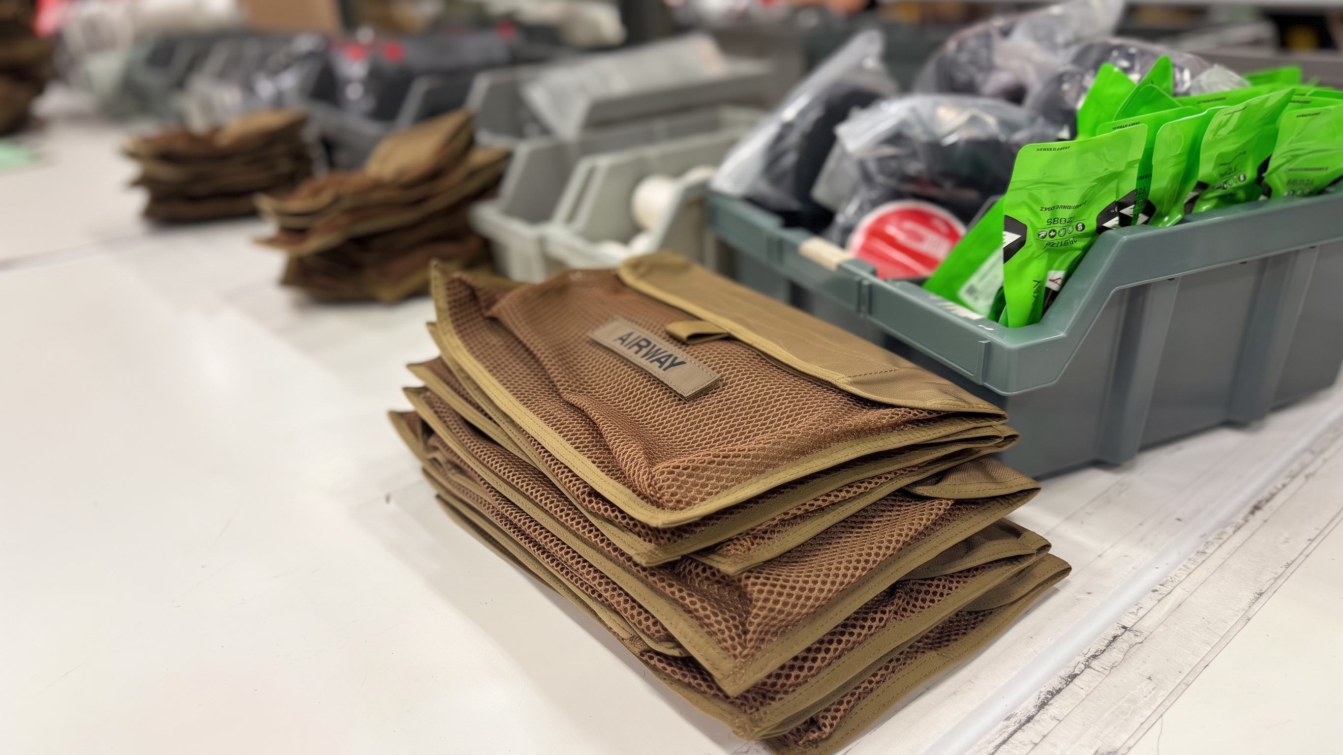 Stacked mesh organizer pouches beside bins of packaged medical supplies