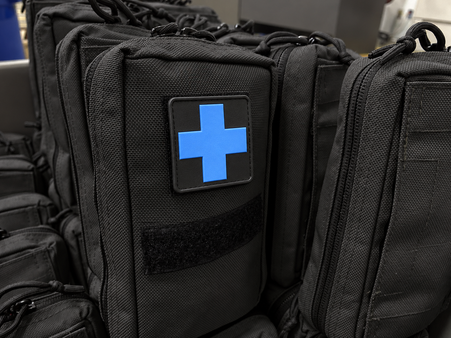 Black medical pouches arranged together, with blue cross patches
