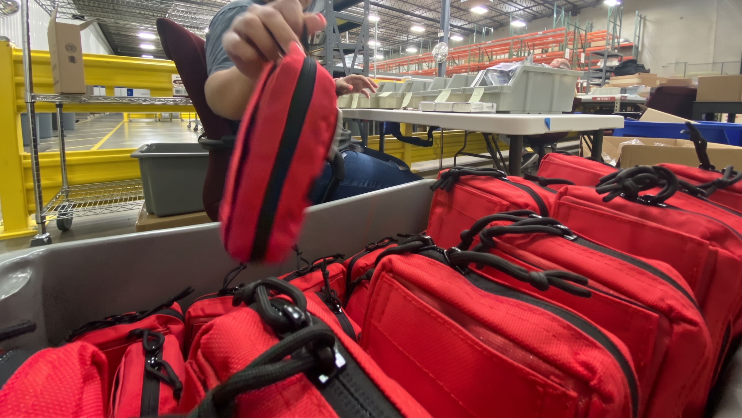 Team member handling red medical kit pouches at a supply workbench